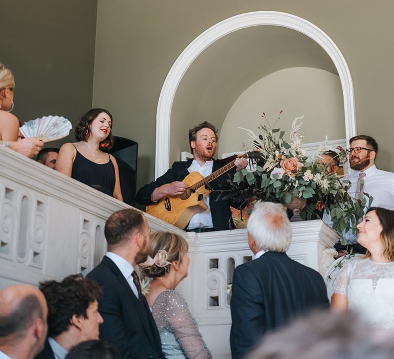 Wedding Guest Playing Guitar During The Wedding Ceremony at Pynes House, Devon