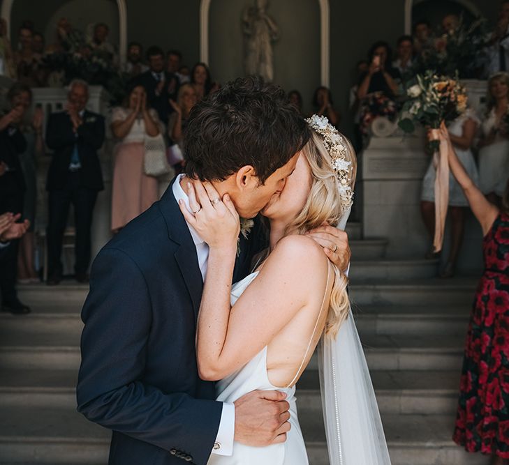 Bride in Slinky Wedding Dress and Groom Kissing During the Wedding Ceremony