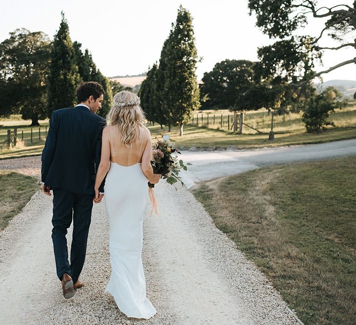 Bride and Groom Walking Down the Country Lane Showing off The Brides Backless Savannah Miller Wedding Dress