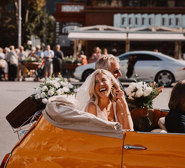 Bride arriving for wedding in a convertible orange fiat 500