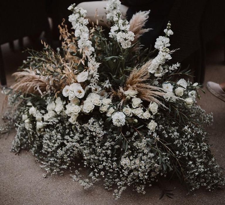 White aisle wedding flowers mixed with foliage and pampas grass