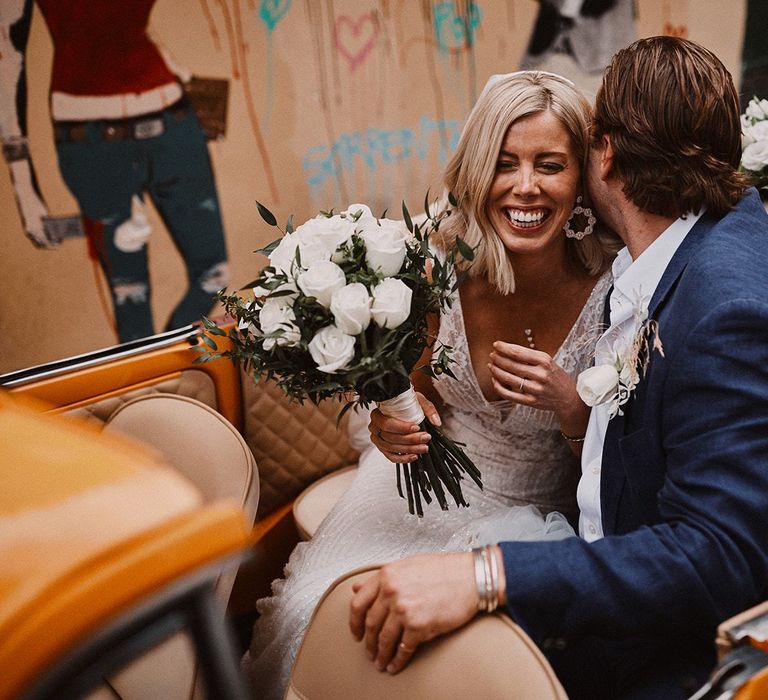 Bride and groom sitting in convertible orange Fiat 500 wedding car