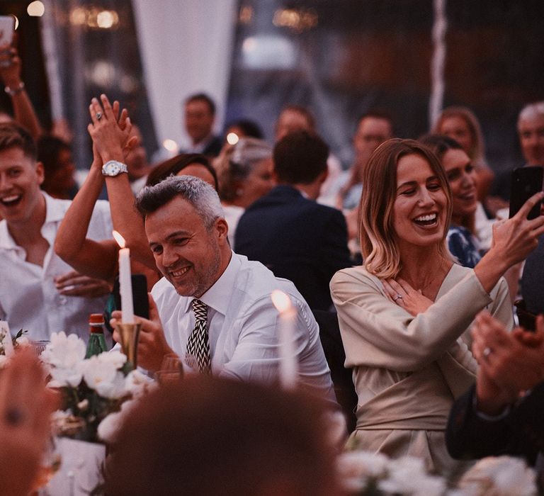 Wedding guests clapping and cheering at wedding reception