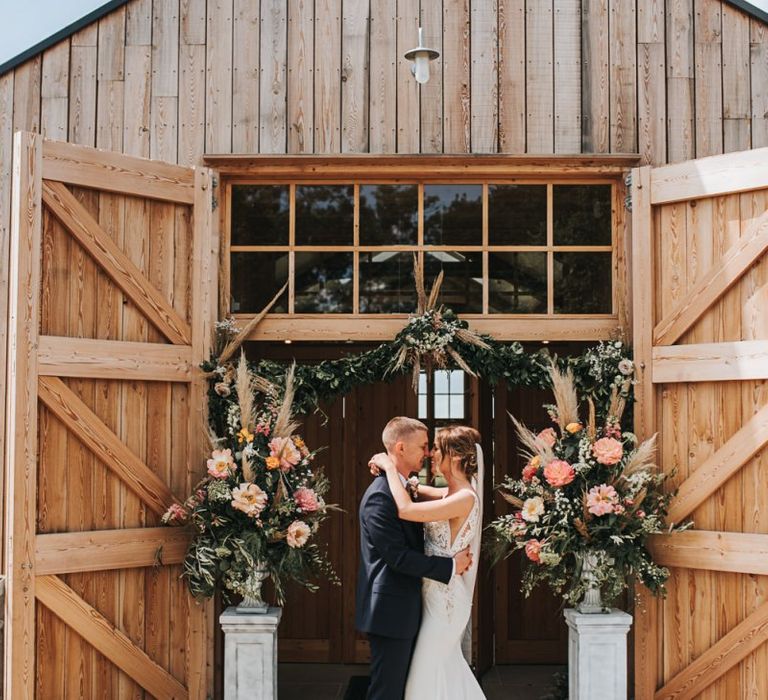 Bride and Groom At Venue Entrance Decorated In Flowers  &amp; Pampas Grass