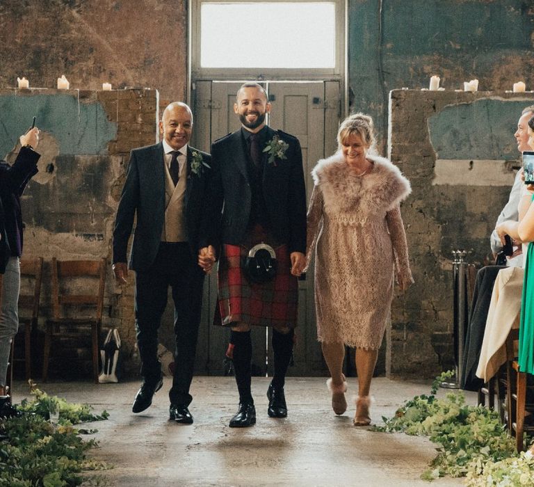 Groom in Red Tartan Kilt Walking Down the Aisle with His Parents