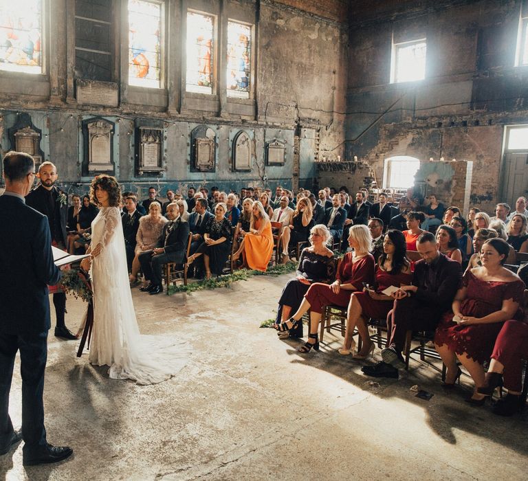 Bride in Bohemian Rue De Seine Wedding Dress and Groom in Red Tartan Kilt Standing at The Asylum Altar