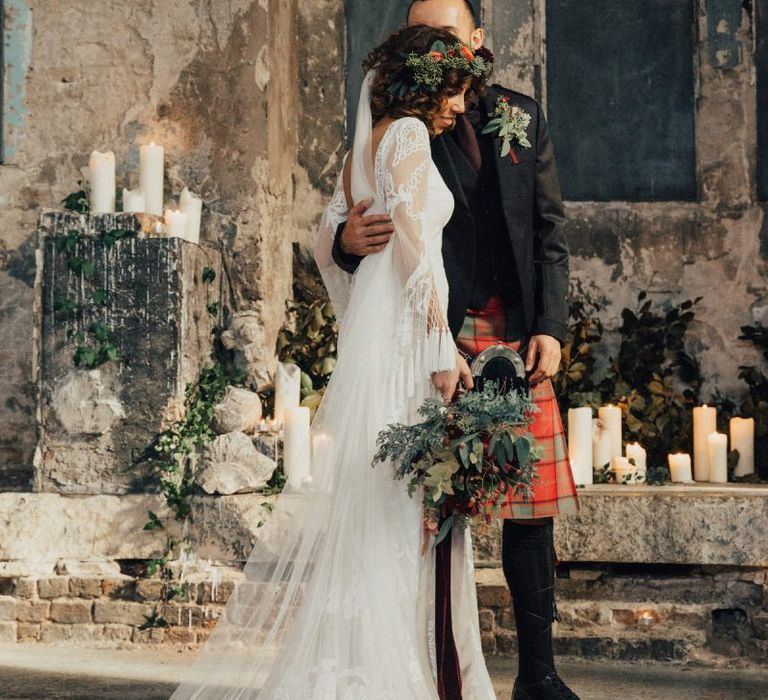 Bride in Bohemian Rue De Seine Wedding Dress and Groom in Red Tartan Kilt  Embracing at The Asylum Altar