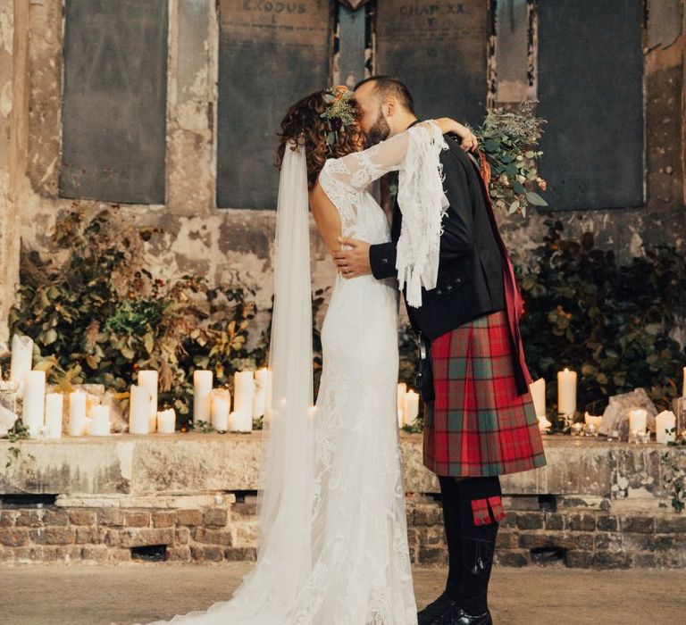 Bride in a Boho Rue De Seine Wedding Dress and Groom in Red Tartan Kilt Kissing After Their Wedding Ceremony