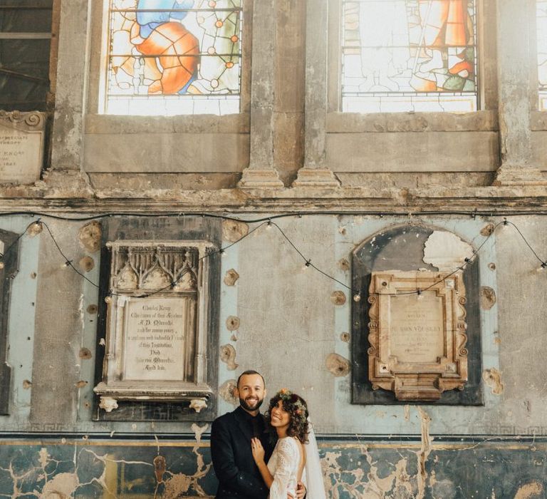 Bride in a Boho Rue De Seine Wedding Dress and Groom in Highland Wear Embracing in The Asylum Wedding Venue