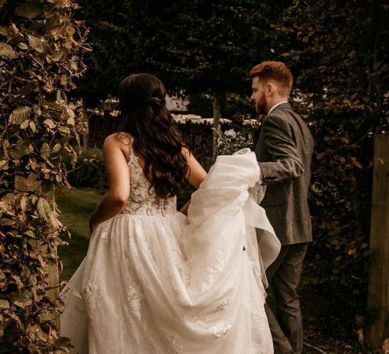 Groom helping his bride with her wedding dress train