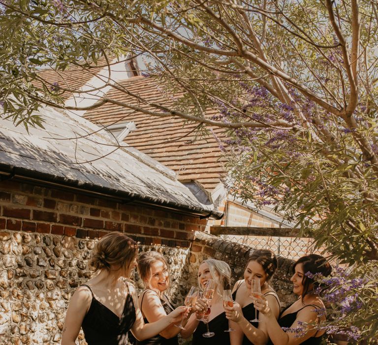 Bridesmaids in black dresses raising a toast