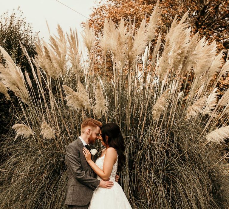 Bride and groom wedding portrait next to pampas grass plant