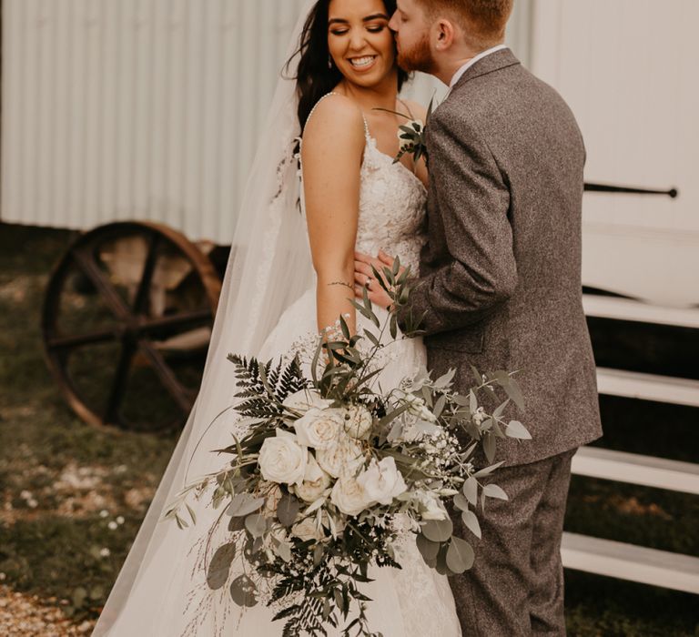 Groom kissing his bride in a Enzoani wedding dress