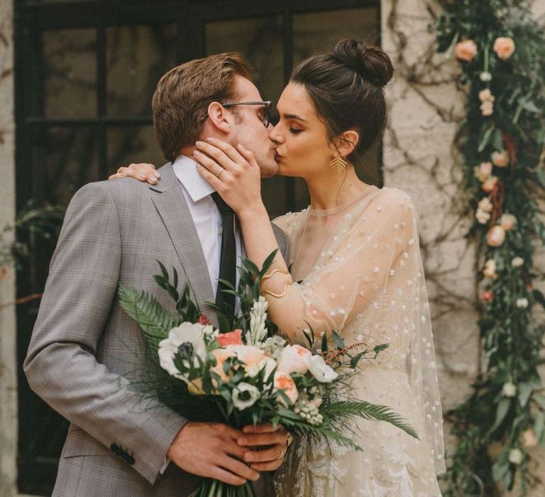 Bride with Top Knot Kissing Her Groom in a Grey Check Suit