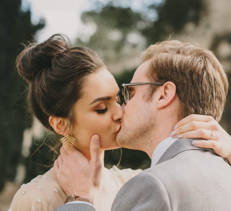 Bride with Top Knot and Gold Leaf Earrings Kissing Her Groom