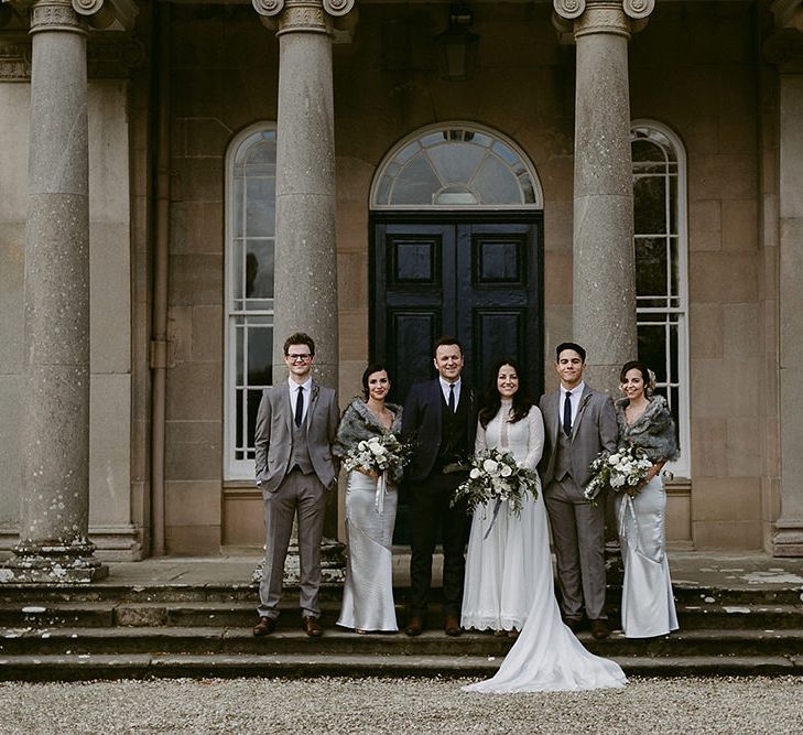 WeddingParty with Bridesmaids in Grey Satin Dresses &amp; Fur Stoles, Bride in a Homemade Wedding Dress with Lace Bodice and Long Sleeves, and Groomsmen in Grey Suits