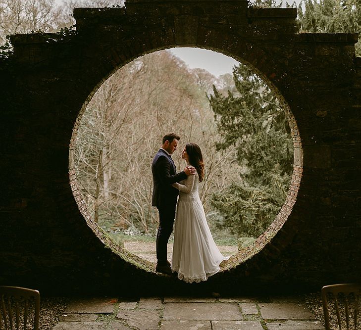 Bride in Homemade Wedding Dress with Lace Long Sleeves and High Neck and Groom in Navy Zara Suit