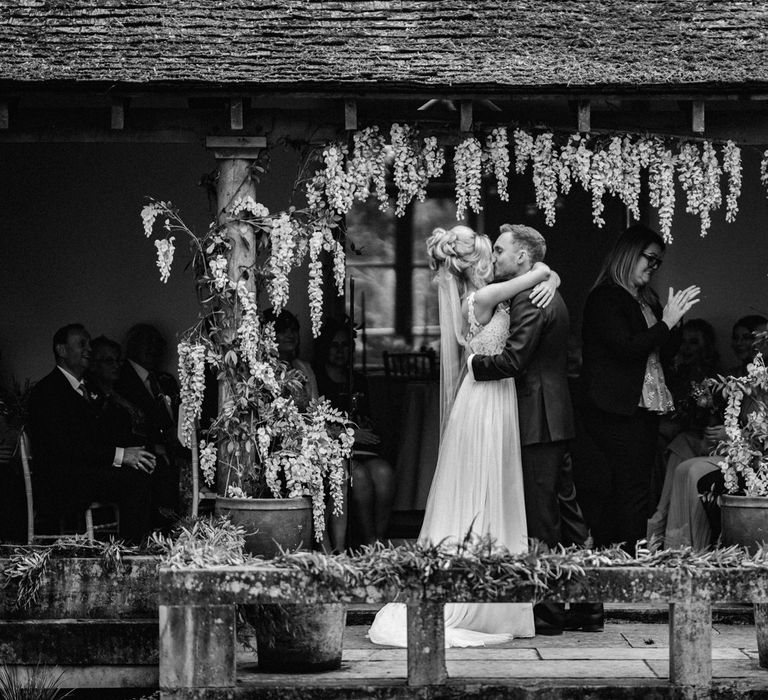 Black and White Portrait of Outdoor Wedding Ceremony with Bride in Stacey by Modeca Wedding Dress and Groom in  Charles Tyrwhitt Suit