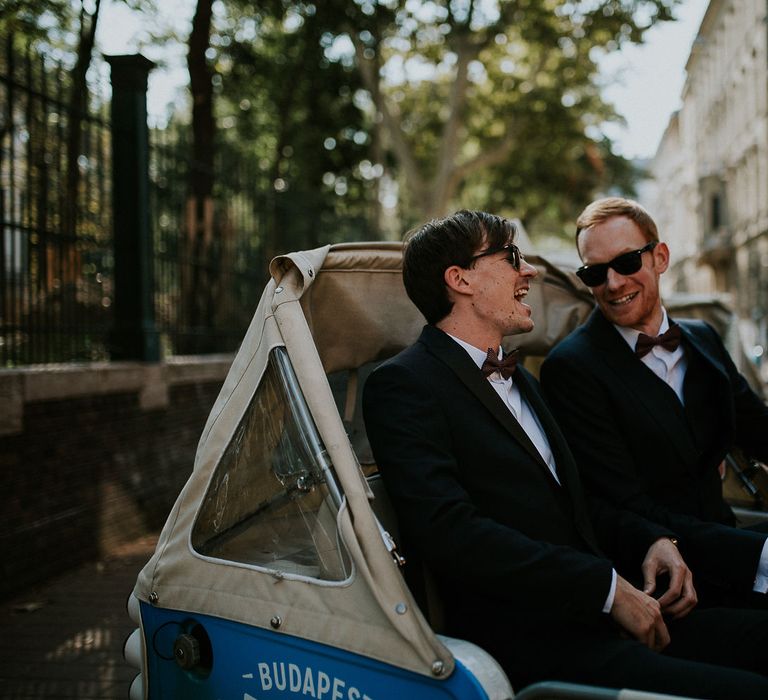 Groom in Black Three-Piece Suit from Hackett with Burgundy Bow Tie from Zara | Groomsman in Black Tuxedo Suit from Moss Bros. with Burgundy Bow Tie from Zara | Tuk Tuk Wedding Transport | Budapest Wedding with Giant Bridal Bouquet, Tuk Tuks and Cadillac | Jágity Fanni Fotográfus