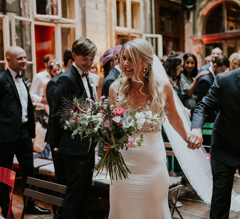 Bride in Lila Gown by Alexandra Grecco with Fitted Silk Crepe Skirt and Sheer Italian Tulle Bodice Covered in Floral Lace Applique | Theia Bridal Veil with Petal Detail | Oversized  Bouquet with Pink, Red and White Flowers and Foliage | Budapest Wedding with Giant Bridal Bouquet, Tuk Tuks and Cadillac | Jágity Fanni Fotográfus