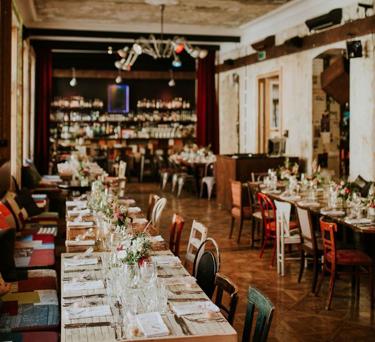 Wedding Reception at Brody Studios in Budapest, Hungary | Long Wooden Tables | Mismatched Chairs | Colourful Lights | Budapest Wedding with Giant Bridal Bouquet, Tuk Tuks and Cadillac | Jágity Fanni Fotográfus