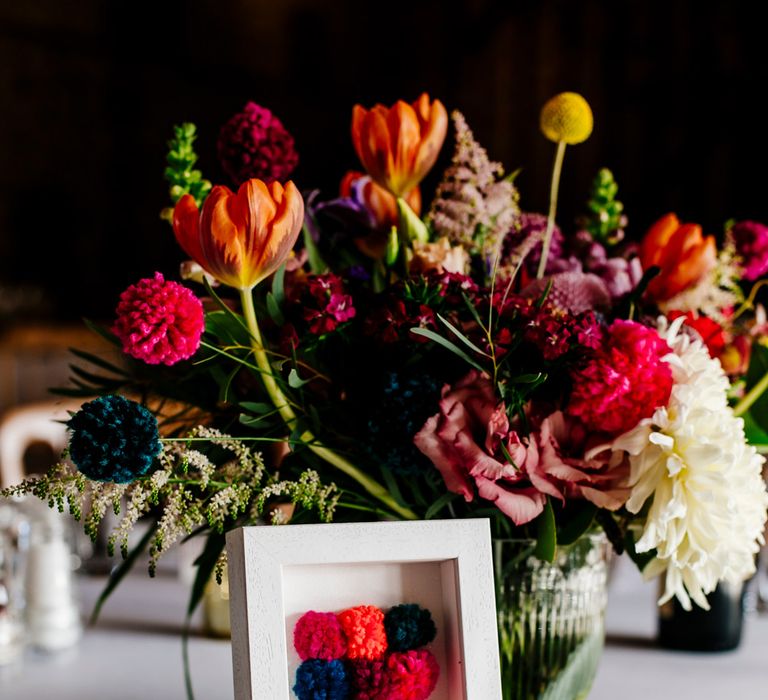 Table Centrepiece with Pom Pom Table Number | Colourful Alternative Winter Wedding at Upwaltham Barns, Sussex | Epic Love Story Photography