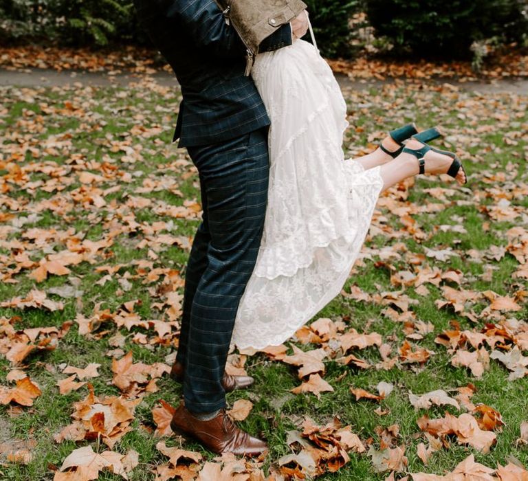 Bride and groom embrace wearing green shoes and boho style dress