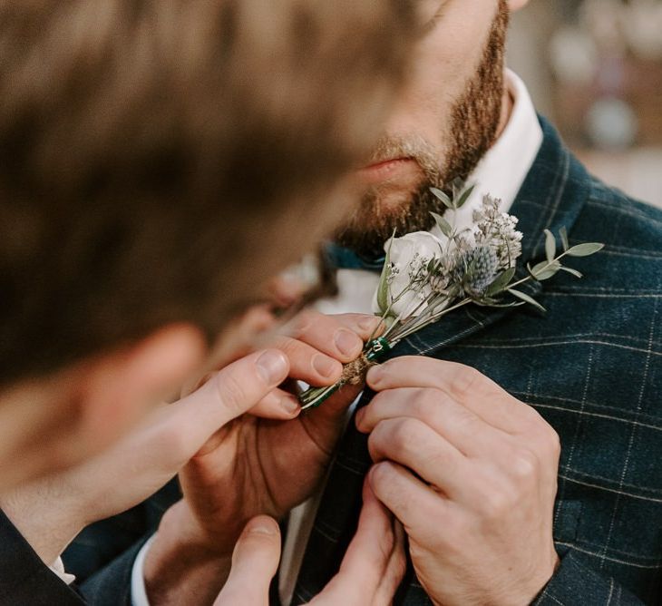 Groom wearing checked suit with white floral buttonhole