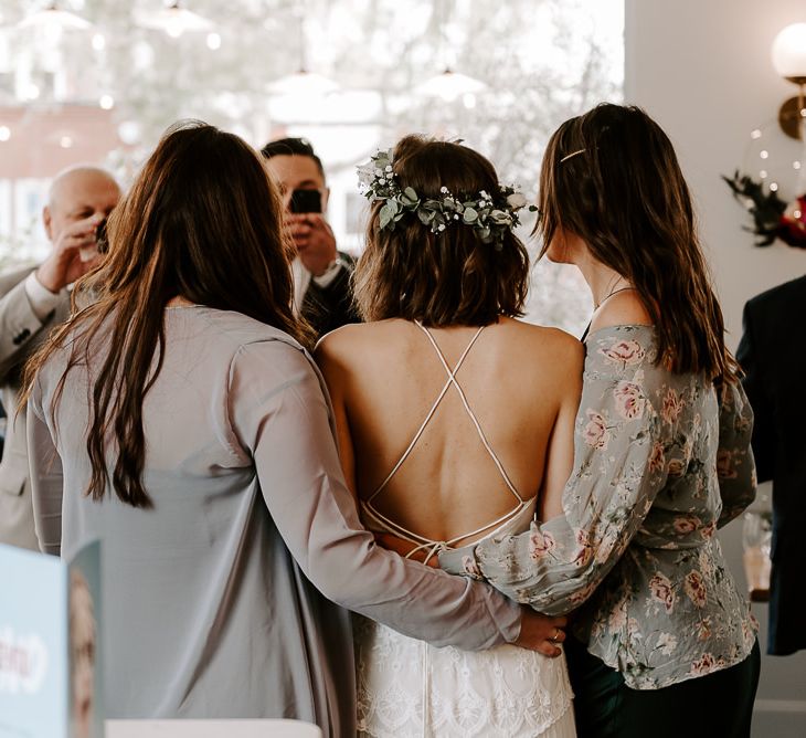 Brides laced back boho style dress with white floral hair crown at intimate reception