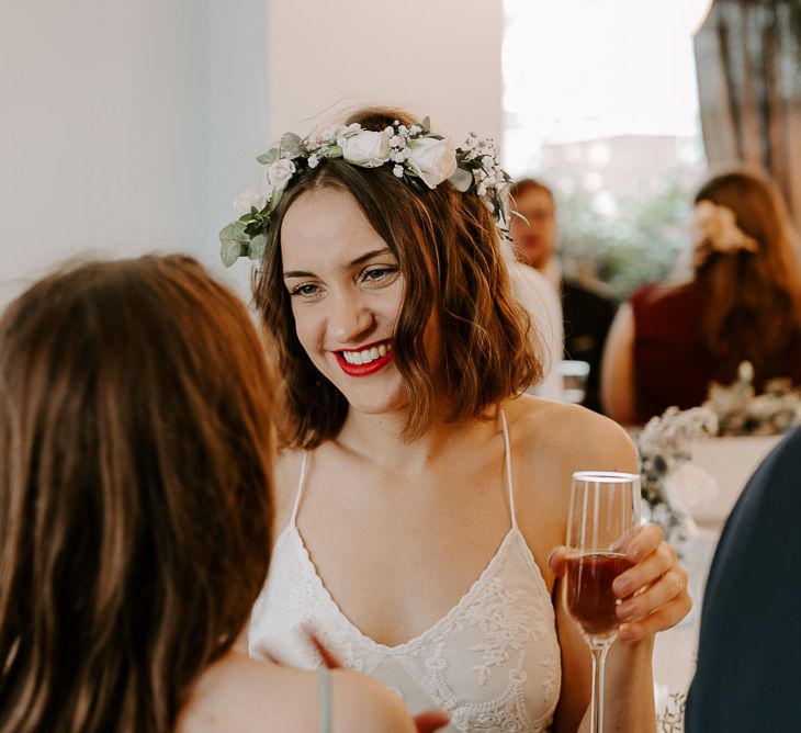 Bride wearing white floral hair crown with laced boho dress and statement red lip