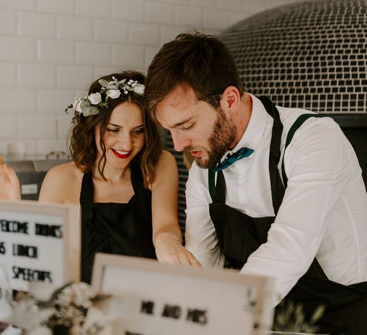 Bride and groom at Italian restaurant for intimate reception with pizza making and black and white wedding signs