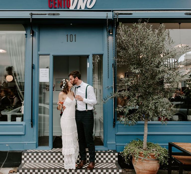 Bride and groom embrace outside of Italian restaurant for intimate reception wearing Spell And The Gypsy dress