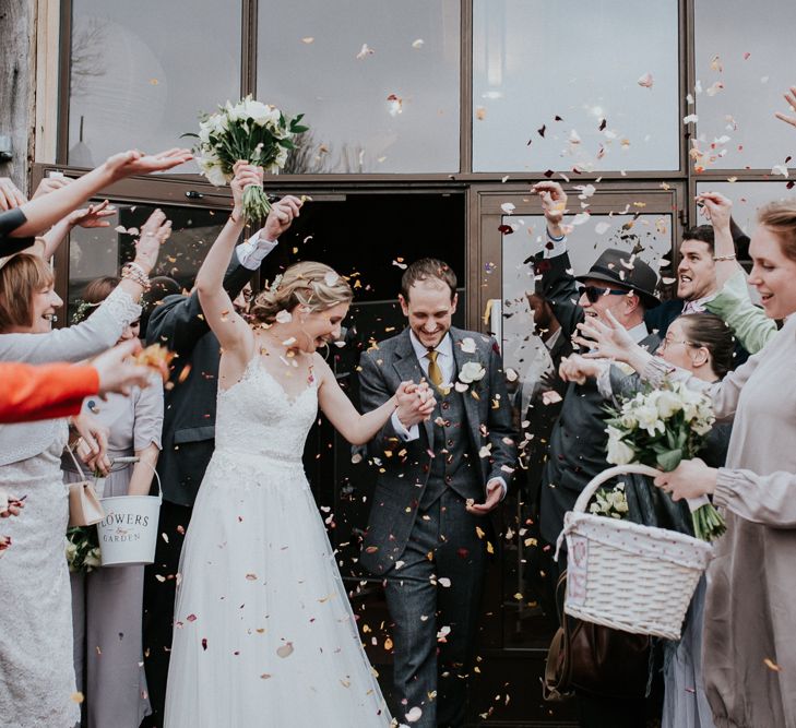 Confetti Moment | Bride in Essense of Australia Gown | Groom in  Grey Suit | Gold, Grey &amp; Green Rustic Wedding at The Gilbert White’s 16th Century Hampshire Barn | Joasis Photography