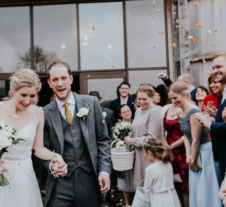 Confetti Moment | Bride in Essense of Australia Gown | Groom in  Grey Suit | Gold, Grey &amp; Green Rustic Wedding at The Gilbert White’s 16th Century Hampshire Barn | Joasis Photography