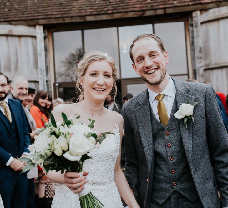 Confetti Moment | Bride in Essense of Australia Gown | Groom in  Grey Suit | Gold, Grey &amp; Green Rustic Wedding at The Gilbert White’s 16th Century Hampshire Barn | Joasis Photography