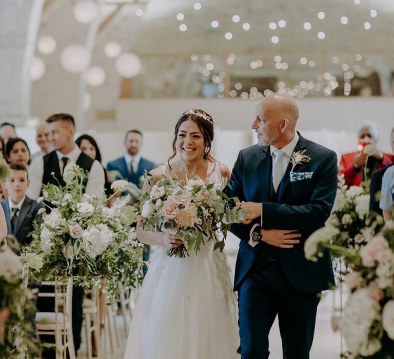 Bride walks down the aisle at Tithe Barn Petersfield with blush bouquet