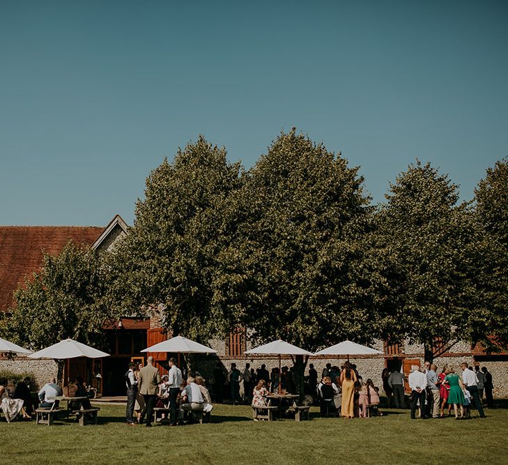 Guests enjoy drinks outside Tithe Barn Petersfield wedding venue