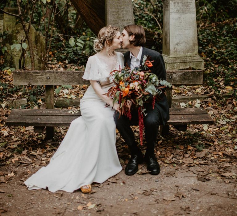 Bride and Groom Embracing on a Cemetery Park Bench