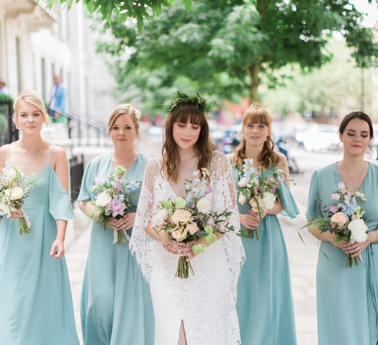 Bride in Grace Loves Lace Verdelle Dress with V-Neck, Low Square Back, Mid-Thigh Front Split and Lace Cape | Foliage Hair Crown | Gold Flat Gianvito Rossi Sandals | Bridesmaids in Mismatched Marine Green Rewritten Dresses | Pastel Wedding Bouquets | Neon Sign and Marine Green Rewritten Bridesmaids Dresses with Lace Cape Grace Loves Lace Gown | Alain Mbouche Photography