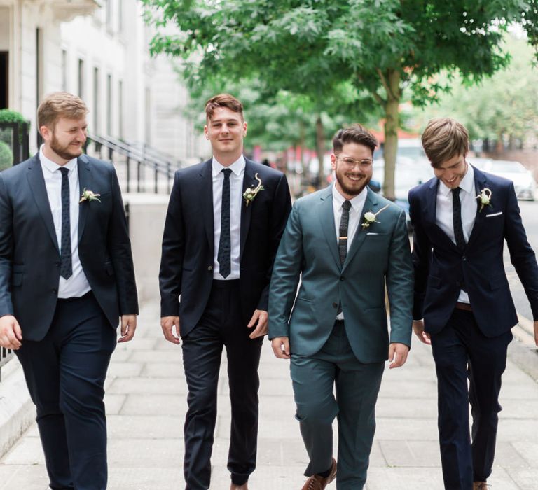 Groom in Blue Reiss Suit with Brown Grenson Shoes | Groomsmen in Navy Suits with Le Colonel Moutarde Ties | Neon Sign and Marine Green Rewritten Bridesmaids Dresses with Lace Cape Grace Loves Lace Gown | Alain Mbouche Photography