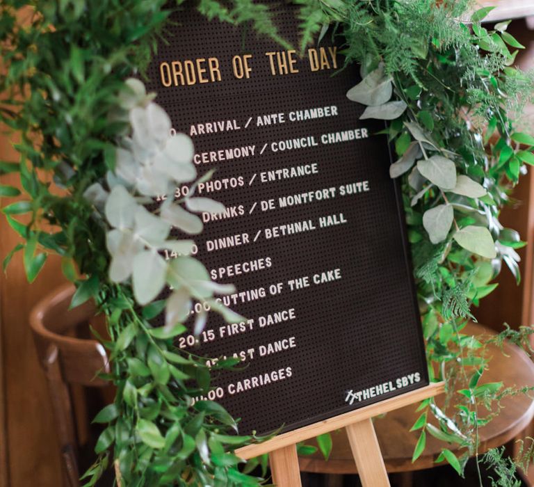 Pin Board Order of the Day Sign | Foliage Drapery | Neon Sign and Marine Green Rewritten Bridesmaids Dresses with Lace Cape Grace Loves Lace Gown | Alain Mbouche Photography