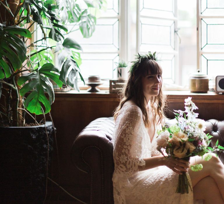 Bride in Grace Loves Lace Verdelle Dress with V-Neck, Low Square Back, Mid-Thigh Front Split and Lace Cape | Foliage Hair Crown | Pastel Bridal Bouquet | Town Hall Hotel Bethnal Green | Neon Sign and Marine Green Rewritten Bridesmaids Dresses with Lace Cape Grace Loves Lace Gown | Alain Mbouche Photography