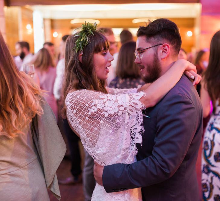 Bride in Grace Loves Lace Verdelle Dress with V-Neck, Low Square Back, Mid-Thigh Front Split and Lace Cape | Foliage Hair Crown | Groom in Blue Reiss Suit with Brown Grenson Shoes | First Dance at Town Hall Hotel Bethnal Green | Neon Sign and Marine Green Rewritten Bridesmaids Dresses with Lace Cape Grace Loves Lace Gown | Alain Mbouche Photography