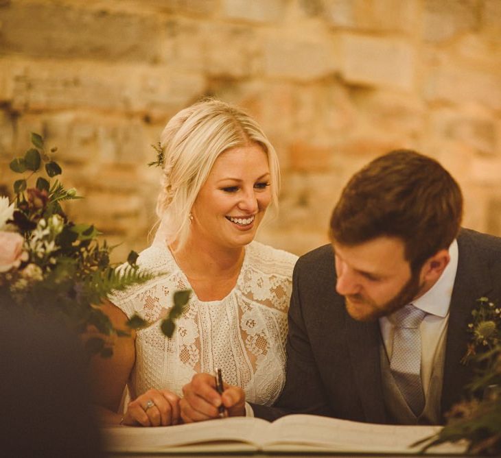 Bride and groom sign the wedding register at Almonry Barn