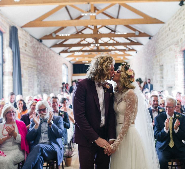 Wedding Ceremony with Bride in Separates and Flower Crown and Groom in Burgundy Suit Kissing