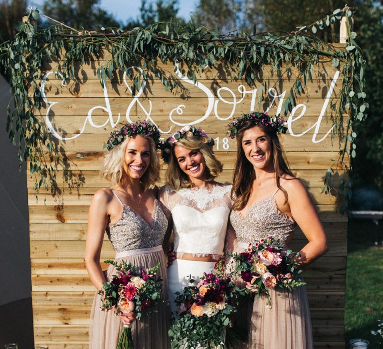 Bridesmaids in Needle &amp; Thread Dresses with Bride in Separates Standing in Front of a Wooden Backdrop