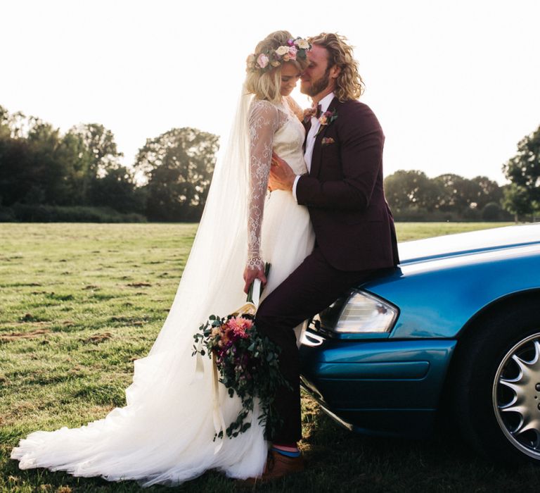 Bride and Groom Sitting on Their Blue Car