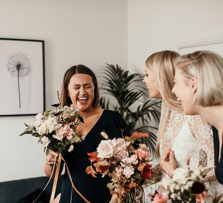 Bridesmaids in black dresses with pink floral bouquets