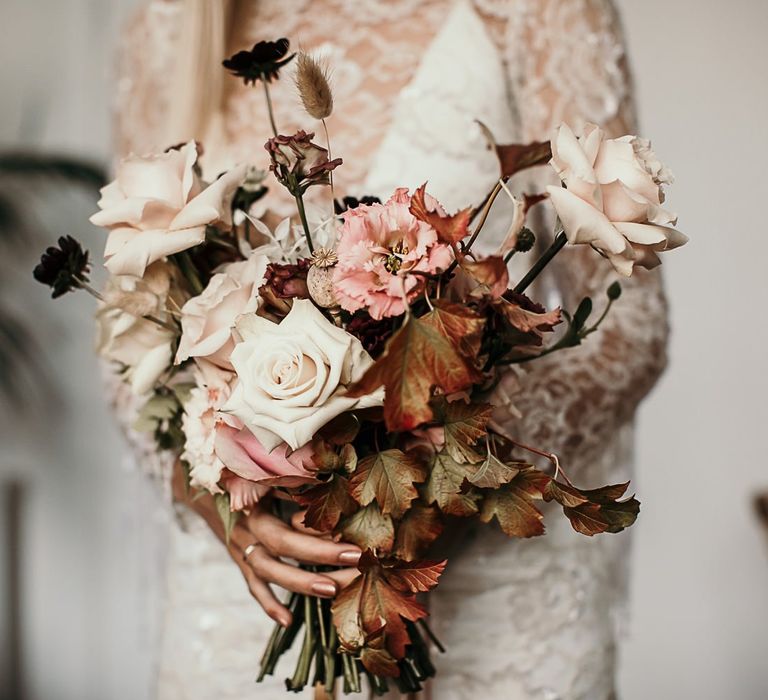 Lace and beaded boho bridal dress with tassel detailing and a pink bouquet