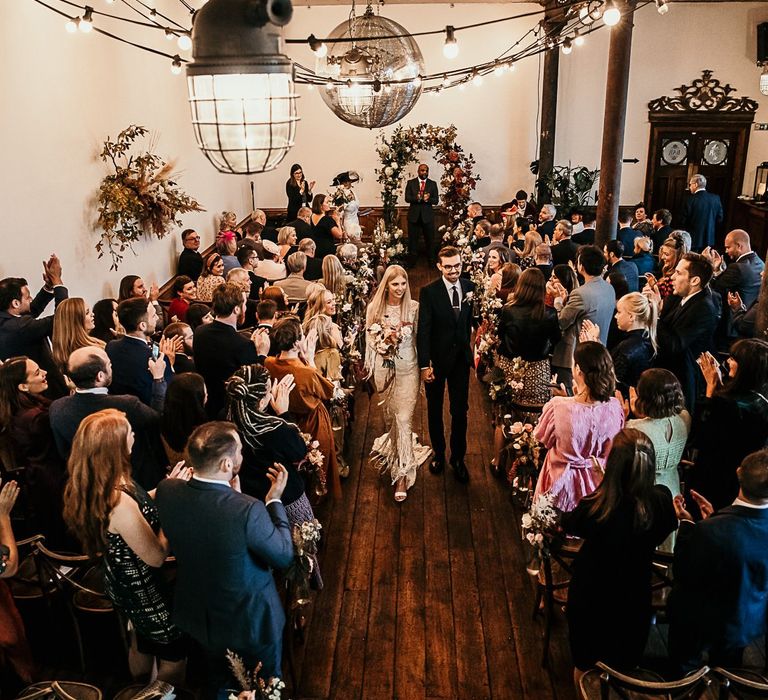 Bride and groom tie the knot at Clapton Country Club wedding ceremony with botanical styling and festoon lighting